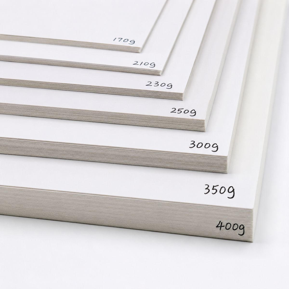 A fanned stack of bleach card sheets showing their gsm weights on the edge