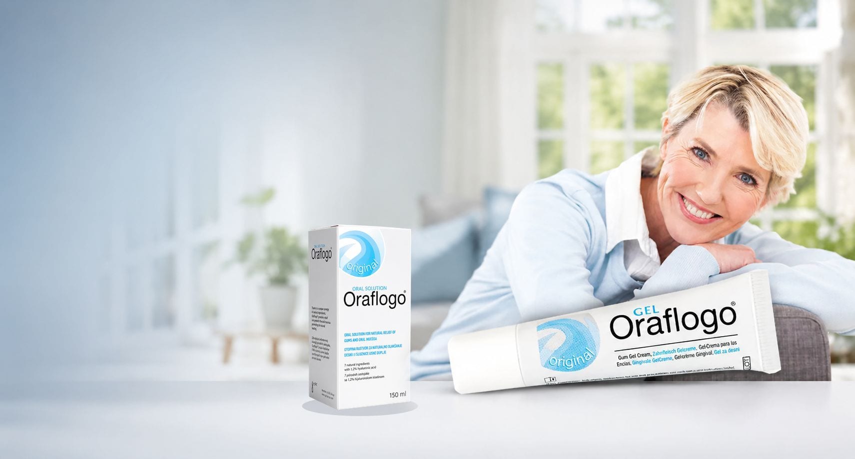 A smiling woman resting beside Oraflogo Gel and Oraflogo Oral Solution in a bright living room